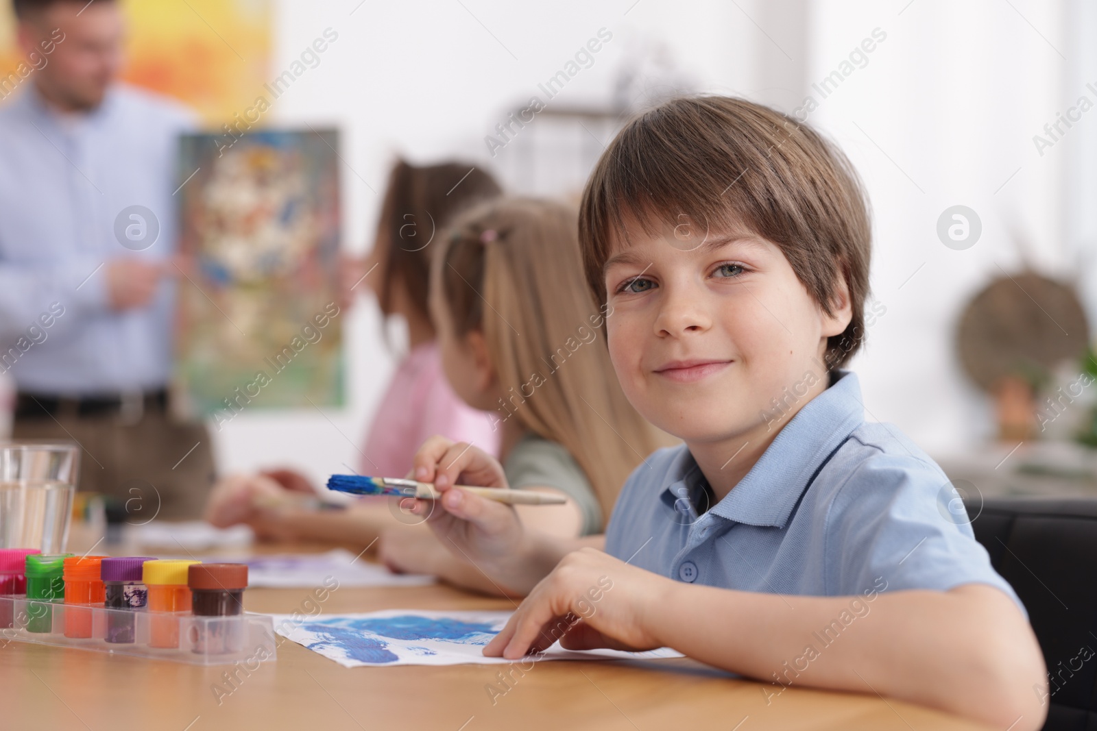 Kids with teacher at painting lesson indoors, selective focus. Learning to draw Photo of Kids with teacher at painting lesson indoors, selective focus. Learning to draw