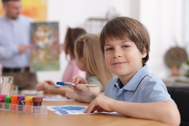 Photo of Kids with teacher at painting lesson indoors, selective focus. Learning to draw