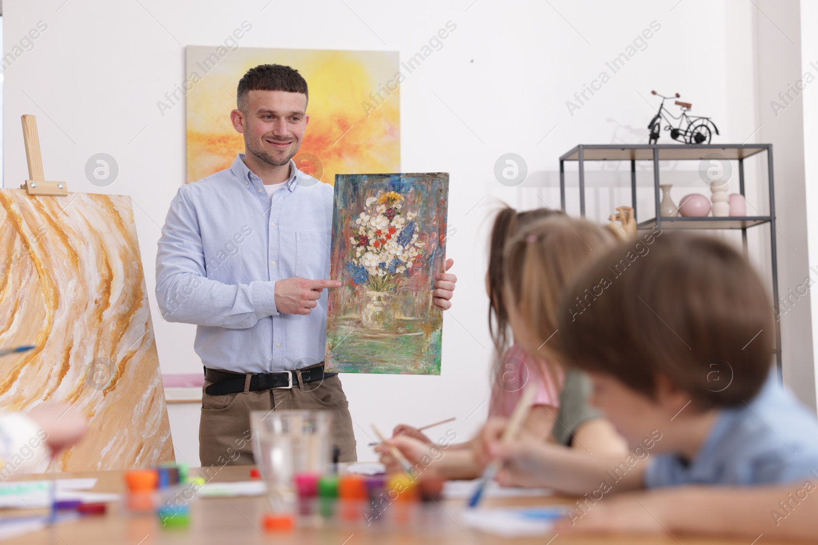Kids with teacher at painting lesson indoors. Learning to draw Photo of Kids with teacher at painting lesson indoors. Learning to draw