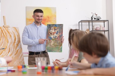 Photo of Kids with teacher at painting lesson indoors. Learning to draw