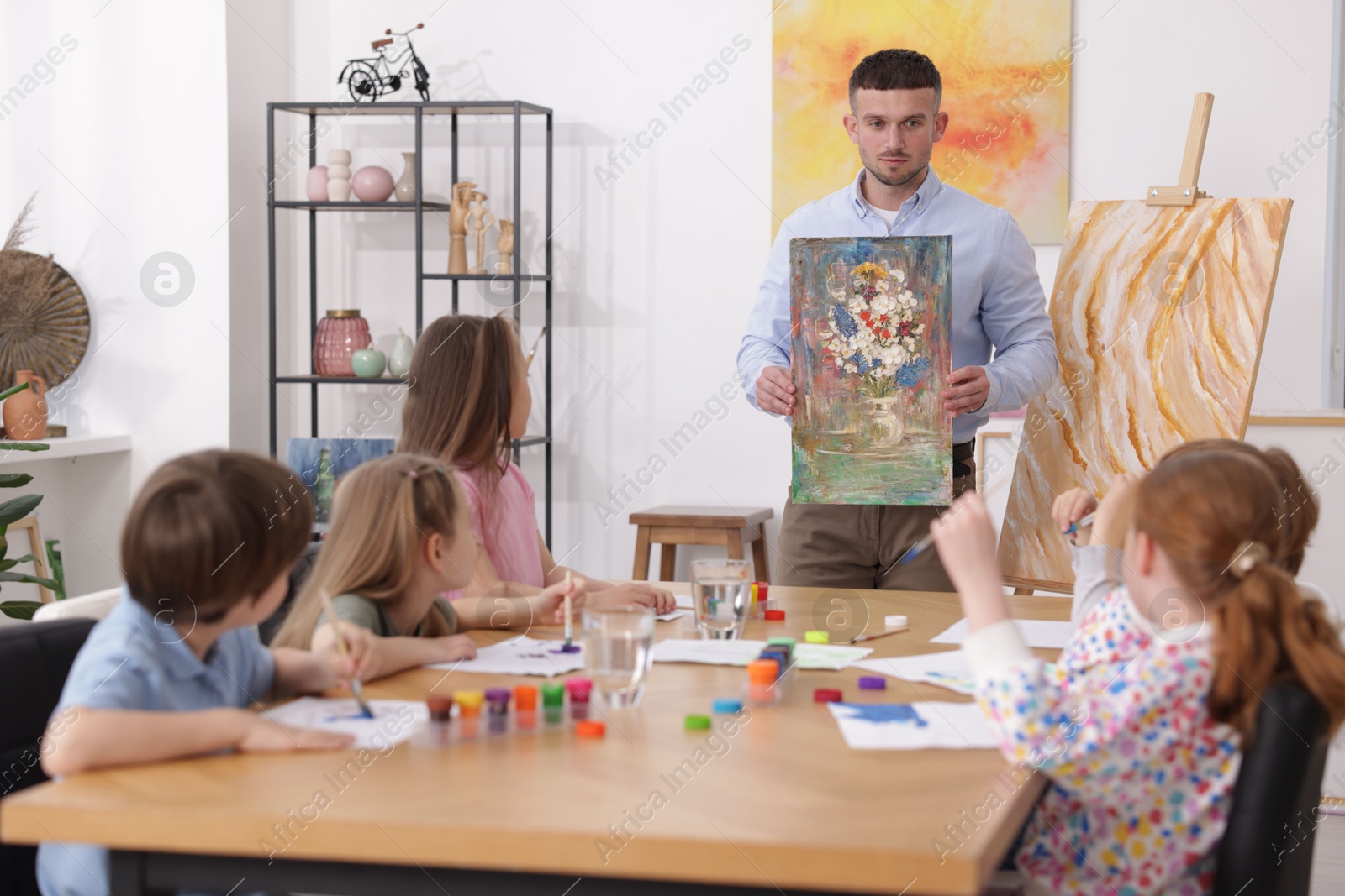 Man teaching kids to draw at painting lesson indoors Photo of Man teaching kids to draw at painting lesson indoors