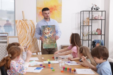 Photo of Man teaching kids to draw at painting lesson indoors