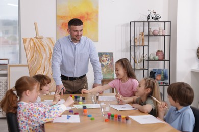 Photo of Man teaching kids to draw at painting lesson indoors
