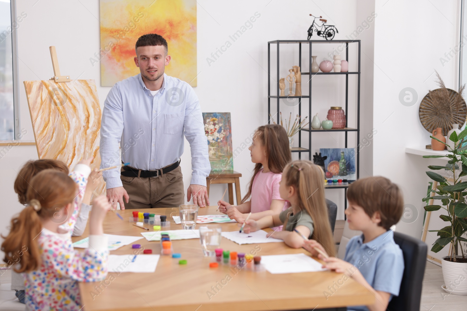 Man teaching kids to draw at painting lesson indoors Photo of Man teaching kids to draw at painting lesson indoors