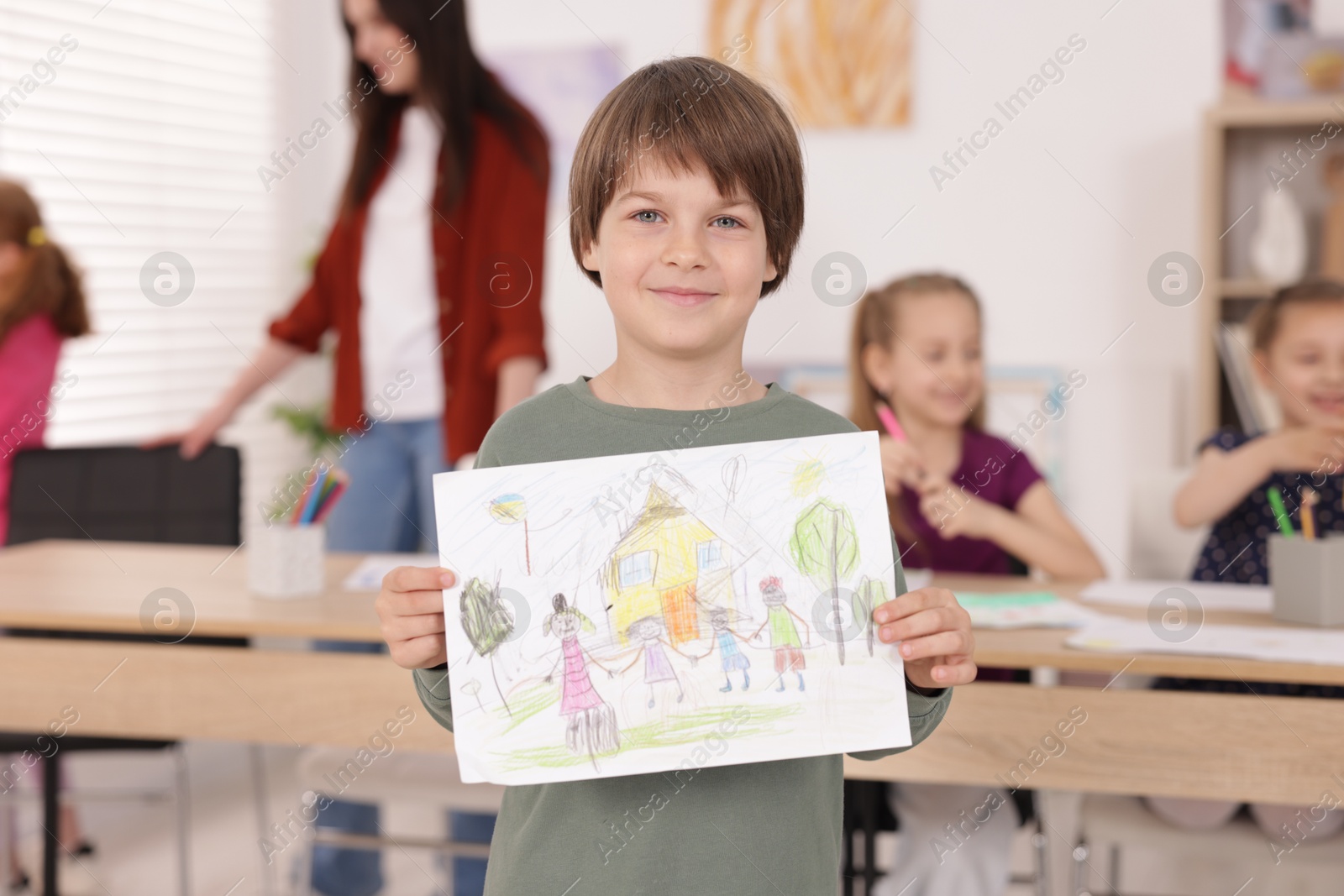 Cute boy showing his drawing during painting lesson indoors, selective focus Photo of Cute boy showing his drawing during painting lesson indoors, selective focus