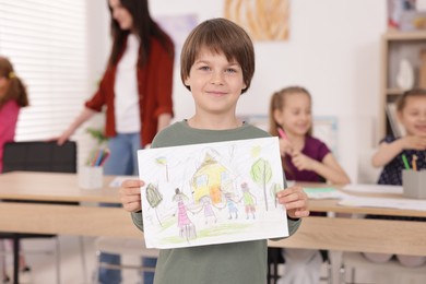 Photo of Cute boy showing his drawing during painting lesson indoors, selective focus