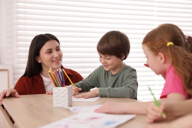 Photo of Woman teaching kids to draw at painting lesson indoors