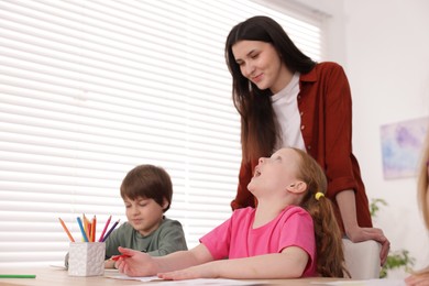 Photo of Woman teaching kids to draw at painting lesson indoors