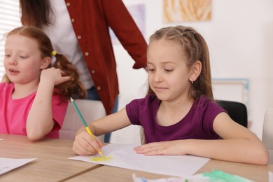 Photo of Kids with teacher at painting lesson indoors. Learning to draw