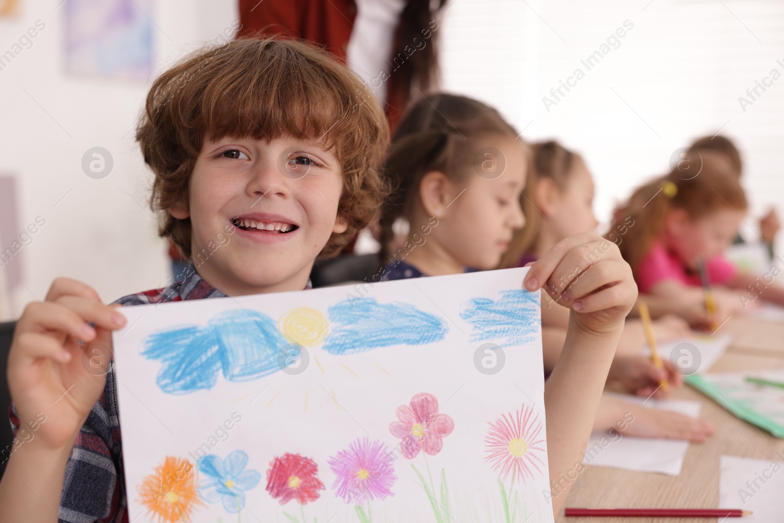 Cute boy showing his drawing during painting lesson indoors, selective focus Photo of Cute boy showing his drawing during painting lesson indoors, selective focus