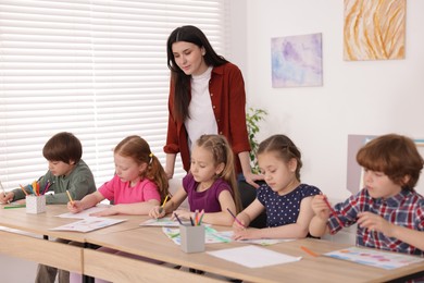 Photo of Woman teaching kids to draw at painting lesson indoors