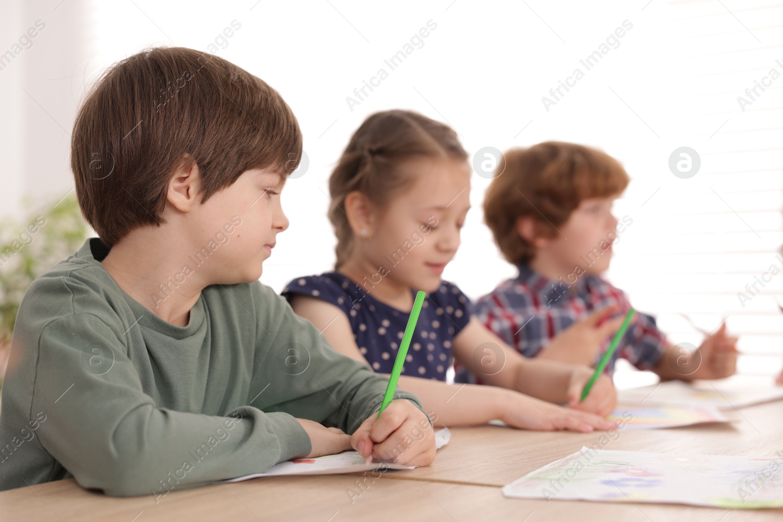 Kids painting at table indoors, selective focus. Learning to draw Photo of Kids painting at table indoors, selective focus. Learning to draw