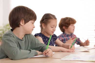 Photo of Kids painting at table indoors, selective focus. Learning to draw