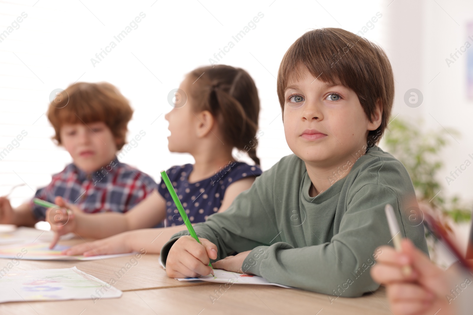 Kids painting at table indoors, selective focus. Learning to draw Photo of Kids painting at table indoors, selective focus. Learning to draw