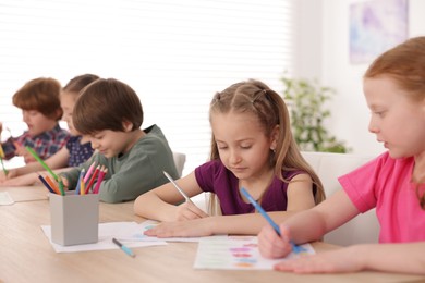Photo of Kids painting at table indoors, selective focus. Learning to draw