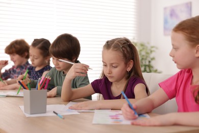 Photo of Kids painting at table indoors, selective focus. Learning to draw