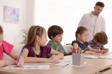 Photo of Kids with teacher at painting lesson indoors, selective focus. Learning to draw