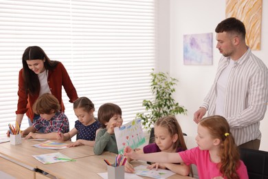 Photo of Kids with teachers at painting lesson indoors. Learning to draw