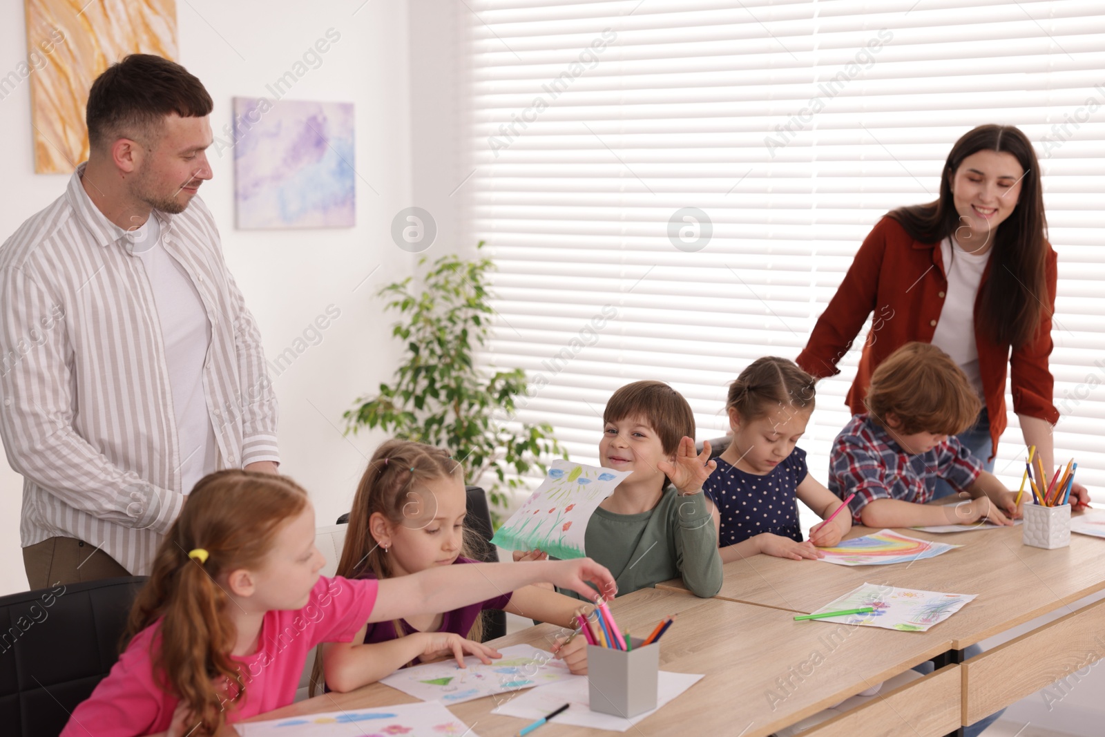 Kids with teachers at painting lesson indoors. Learning to draw Photo of Kids with teachers at painting lesson indoors. Learning to draw