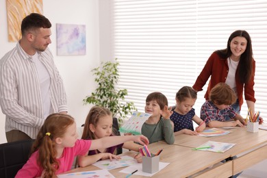 Photo of Kids with teachers at painting lesson indoors. Learning to draw