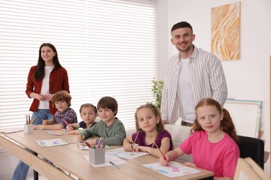 Photo of Kids with teachers at painting lesson indoors. Learning to draw