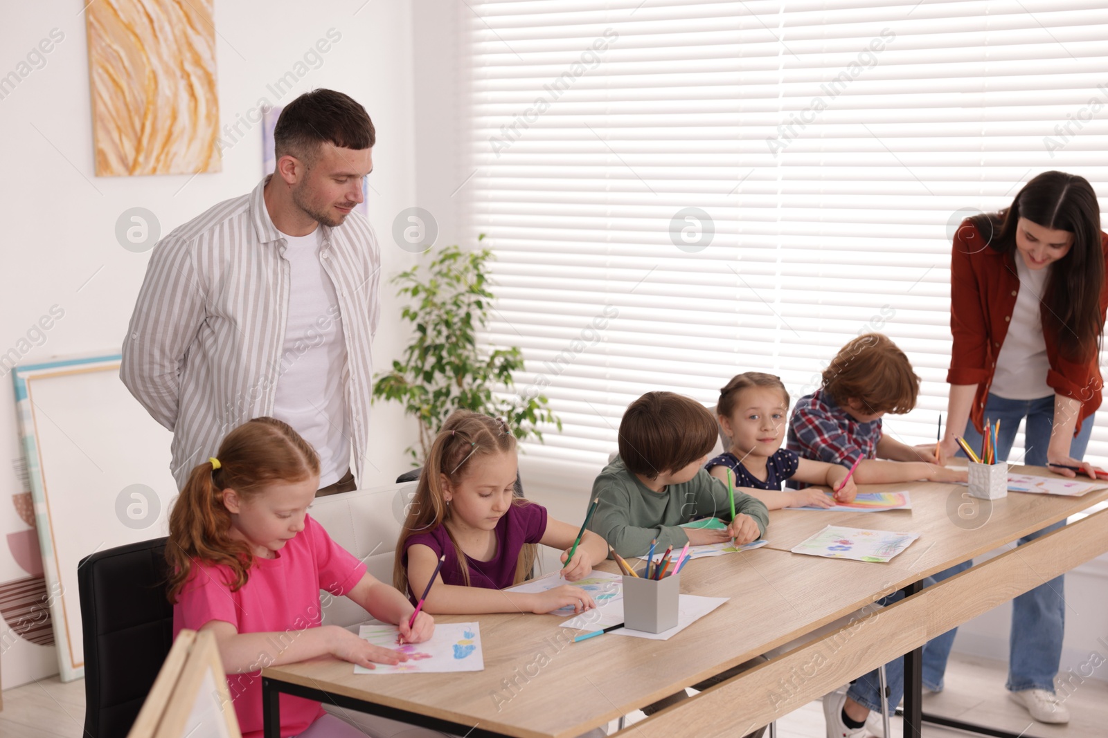 Kids with teachers at painting lesson indoors. Learning to draw Photo of Kids with teachers at painting lesson indoors. Learning to draw