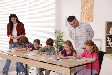Photo of Kids with teachers at painting lesson indoors. Learning to draw