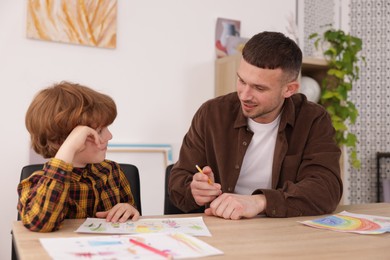 Photo of Man teaching kid to draw at painting lesson indoors