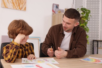 Photo of Man teaching kid to draw at painting lesson indoors