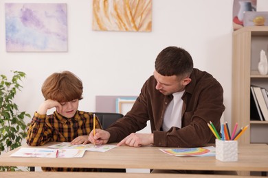Photo of Man teaching kid to draw at painting lesson indoors
