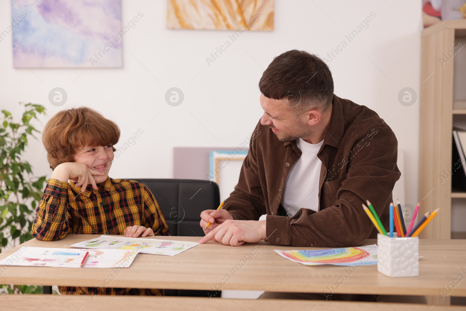 Man teaching kid to draw at painting lesson indoors Photo of Man teaching kid to draw at painting lesson indoors
