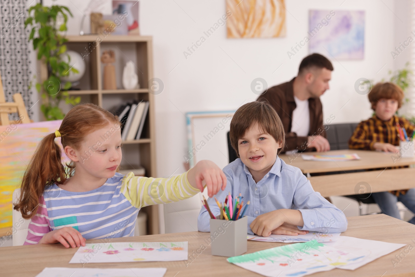 Kids with teacher at painting lesson indoors, selective focus. Learning to draw Photo of Kids with teacher at painting lesson indoors, selective focus. Learning to draw