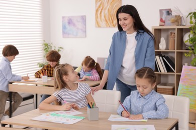 Photo of Woman teaching kids to draw at painting lesson indoors, selective focus