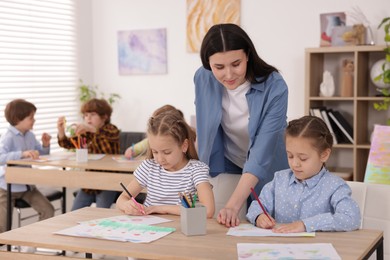 Photo of Woman teaching kids to draw at painting lesson indoors, selective focus