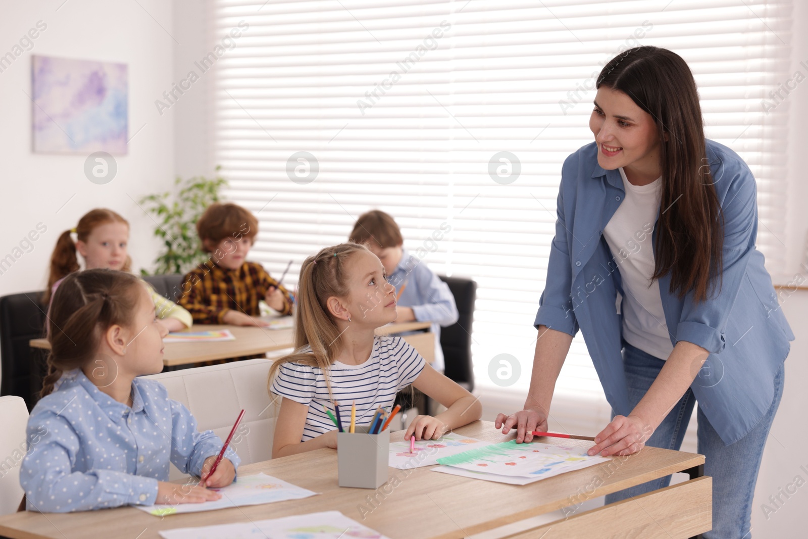 Woman teaching kids to draw at painting lesson indoors, selective focus Photo of Woman teaching kids to draw at painting lesson indoors, selective focus
