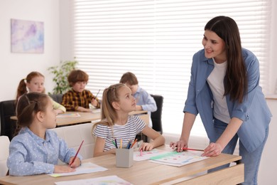 Photo of Woman teaching kids to draw at painting lesson indoors, selective focus