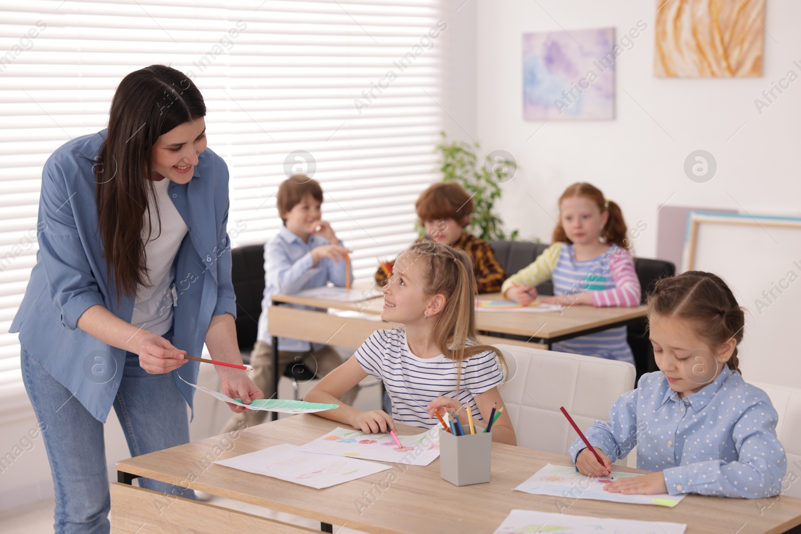 Woman teaching kids to draw at painting lesson indoors, selective focus Photo of Woman teaching kids to draw at painting lesson indoors, selective focus