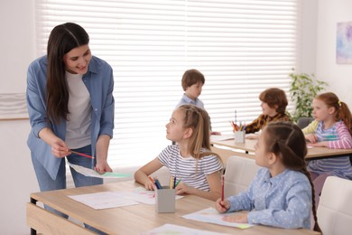 Photo of Woman teaching kids to draw at painting lesson indoors, selective focus