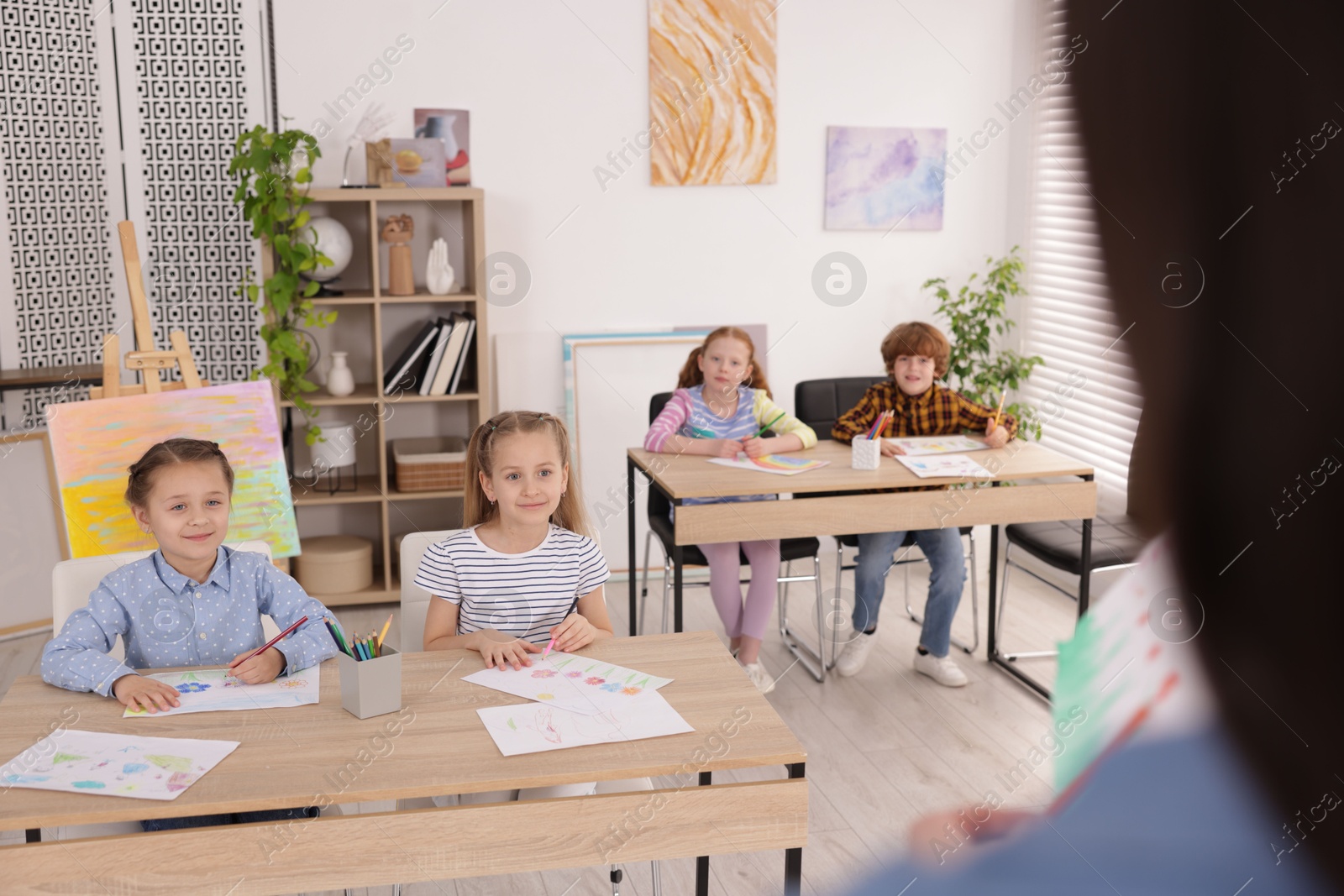 Woman teaching kids to draw at painting lesson indoors, selective focus Photo of Woman teaching kids to draw at painting lesson indoors, selective focus