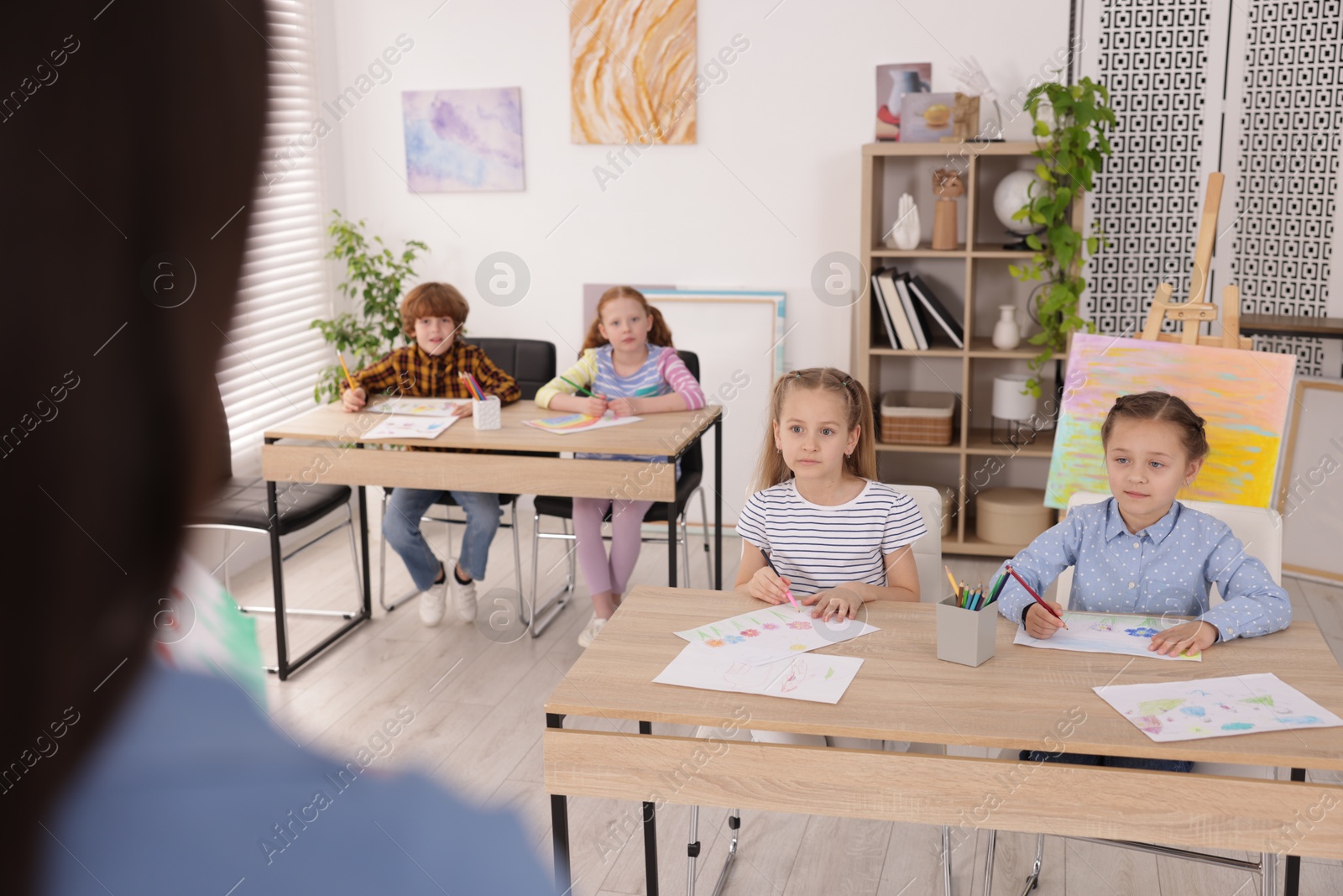 Woman teaching kids to draw at painting lesson indoors, selective focus Photo of Woman teaching kids to draw at painting lesson indoors, selective focus
