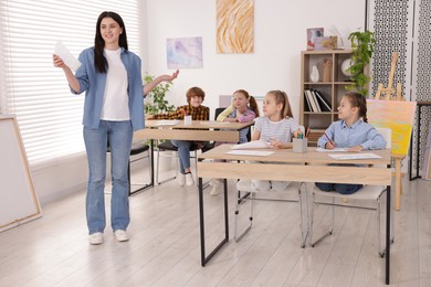Photo of Woman teaching kids to draw at painting lesson indoors