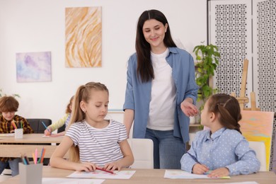 Photo of Woman teaching kids to draw at painting lesson indoors