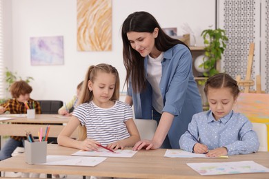 Photo of Woman teaching kids to draw at painting lesson indoors