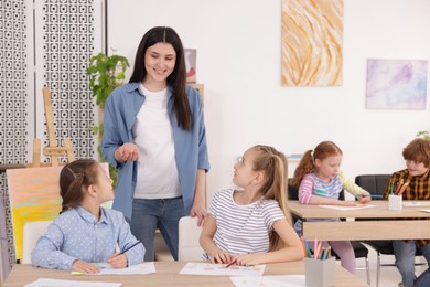 Photo of Woman teaching kids to draw at painting lesson indoors