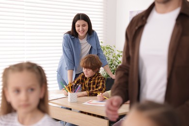 Photo of Kids with teachers at painting lesson indoors, selective focus. Learning to draw