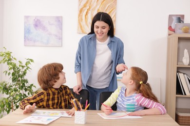 Photo of Woman teaching kids to draw at painting lesson indoors