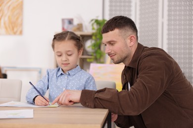 Photo of Man teaching kid to draw at painting lesson indoors