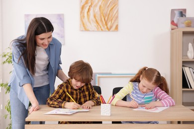 Photo of Woman teaching kids to draw at painting lesson indoors