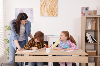 Photo of Woman teaching kids to draw at painting lesson indoors