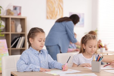 Photo of Kids with teacher at painting lesson indoors, selective focus. Learning to draw